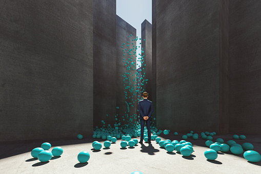 Abstract businessman standing in maze with exploding spheres. This is entirely 3D generated image.
