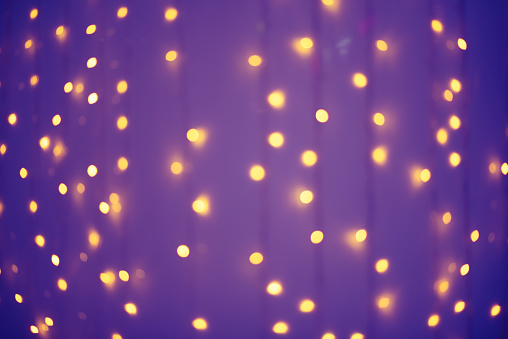 Blurred abstract: blurry orange garlands in the purple background.