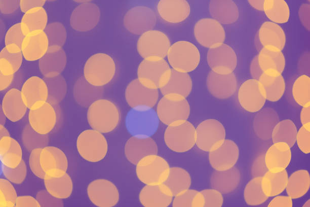 istock Blurred abstract: blurry orange garlands in the purple background 1394305714