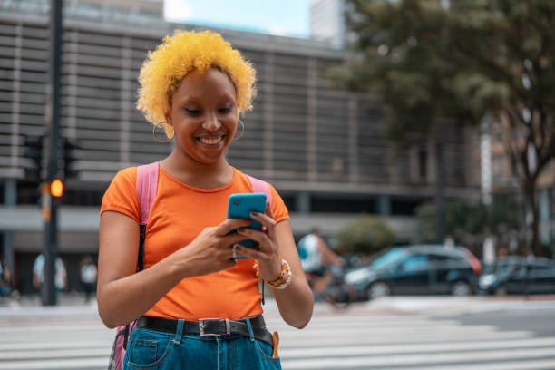 istock Young man with dyed yellow hair using smartphone on the crosswalk 1394305866
