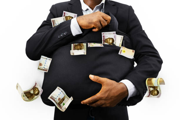 uomo d'affari nero che tiene una borsa nera piena di banconote di naira nigeriana isolate su sfondo bianco, denaro che cade dalla borsa - nigerian culture men africa african culture foto e immagini stock