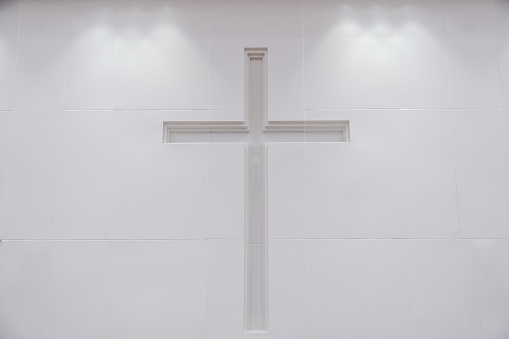 The cross on the white wall of the church