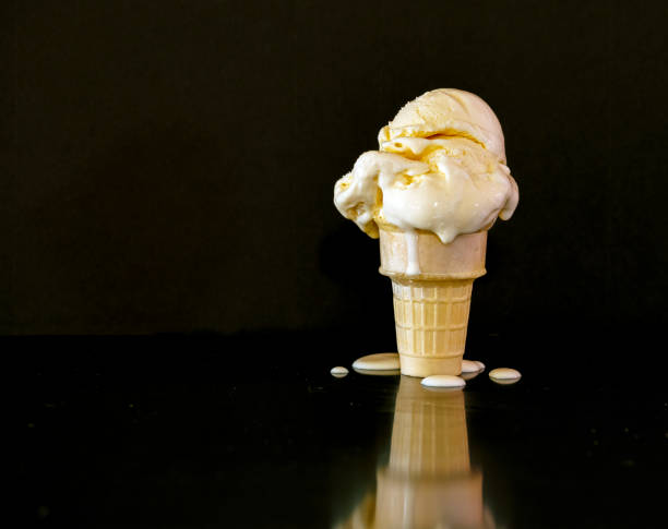 istock Melting, dripping Vanilla Ice Cream cone against a black background with copy space. 1394318530