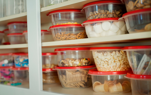 Snack cabinet, stocked, and well-organized with all food in clear plastic containers
