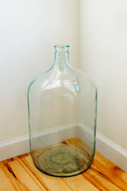 Empty, clear, glass carboy container. 5 gallon size. Large generic glass jug with a wide body and narrow neck. Often used today as a coin jar, but mostly likely used in the past to store liquids.