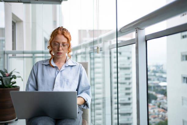 Redhead woman working from home using laptop and smart phone Redhead woman working from home using laptop and smart phone Freelance Writing Jobs stock pictures, royalty-free photos & images