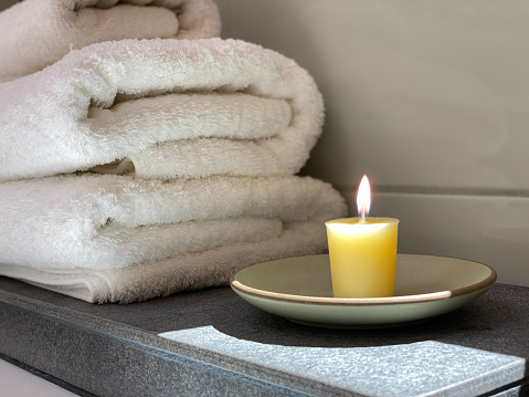 Candle in bathroom by tub with towels