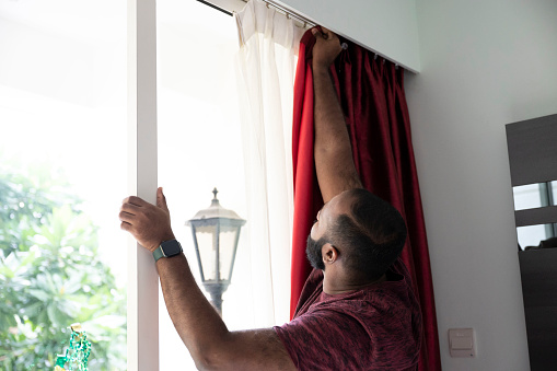 Man putting up new curtains