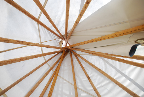 Indoor view of top of tipi with poles and white fabric at campsite