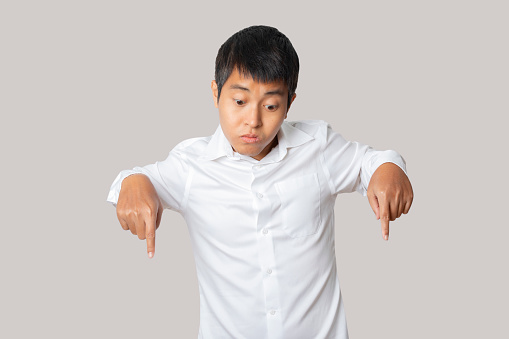 Businessman of pointing down with his finger. presenting gesture.Human emotion face expression concept. Studio shot isolated on gray background. copy space.