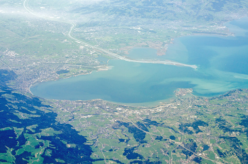 View from the air of the Eastern end of Lake Constance with the mouth of the River Rhine flowing in from the top of the image.  Around the shore are the towns of Lindau, Lochau and Bregenz with the River Rhine flowing into the lake from the top of the image.  Sunny spring morning.