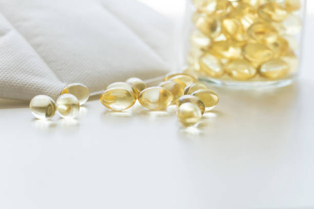 白いn95保護マスク、ソフトジェルまたは油性薬と薬瓶のカプセル - ストックフォト - nutritional supplement fish oil vitamin pill bottle ストックフォトと画像