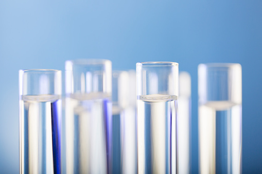 Neatly arranged test tubes containing clear reagent in chemistry laboratory - stock photo