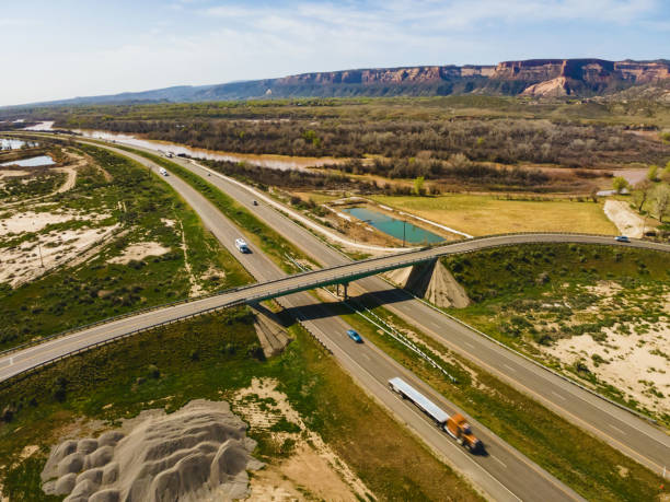 orange flatbed semi truck aerial drone view of vehicles and semi trucks driving on interstate 70 and overpass in western usa fruita colorado photo series - truck desert semi truck orange imagens e fotografias de stock