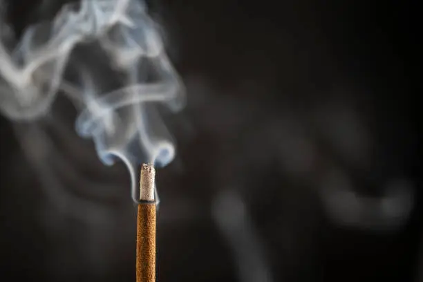 Asian incense stick burning with smoke, close up, macro, copy space
