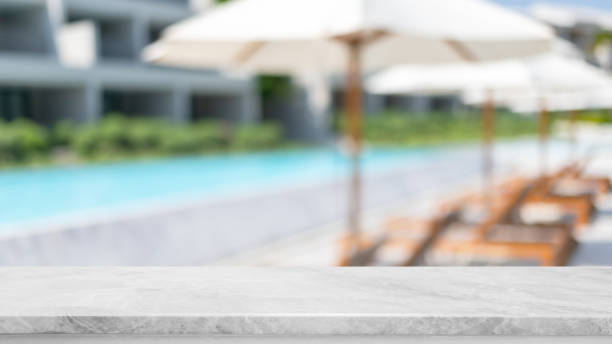istock Empty white marble stone table top and blurred swimming pool in tropical resort in summer banner background - can used for display or montage your products. 1394339221