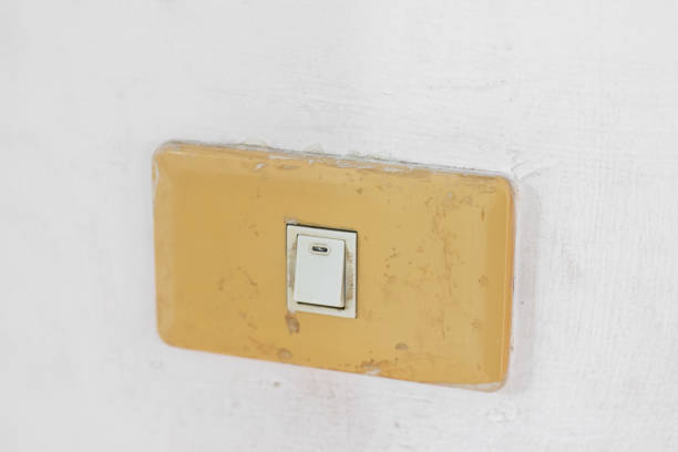 Close up fingers is turning on or turning off the brown old light-switch on stenciled white wall.