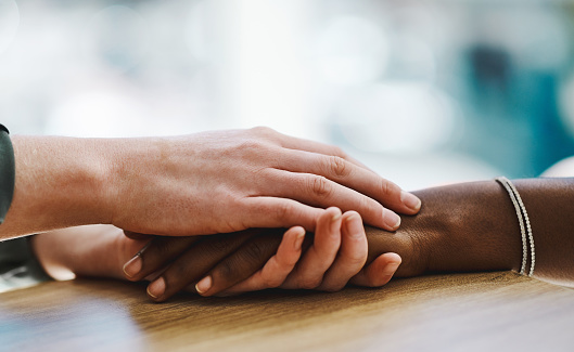 Two diverse women holding hands in comfort