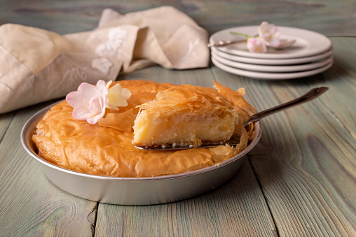Milk pie on semolina with lemon sauce on a wooden table close-up (Greek cuisine)