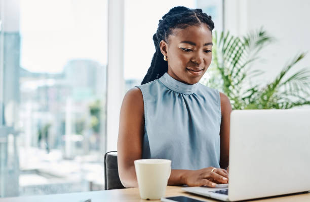 istock Young black businesswoman working on a laptop in an office alone 1394347328