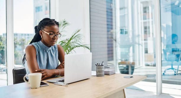 istock Focused young black businesswoman working on a laptop in an office alone 1394347330