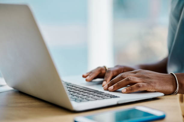 Hands of an african businesswoman browsing on a laptop in an office alone stock photo