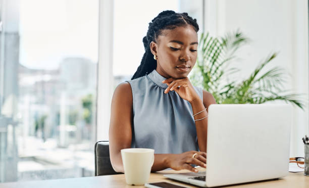 istock Young black businesswoman thinking while working on a laptop in an office alone 1394347397