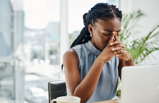 femme d’affaires noire stressée travaillant seule sur un ordinateur portable dans un bureau - stress photos et images de collection