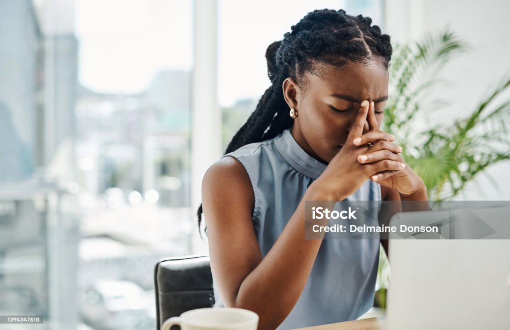 Stressed black businesswoman working on a laptop in an office alone Emotional Stress Stock Photo