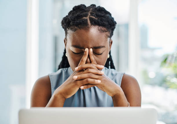 istock African woman suffering with a headache and feeling stressed about deadlines while working on a laptop in an office alone 1394347619