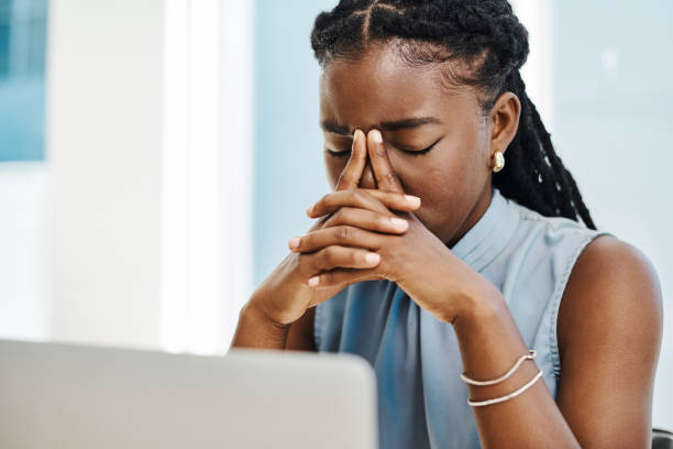 istock Young black businesswoman suffering with a headache and looking stressed out while working on a laptop in an office alone 1394347626