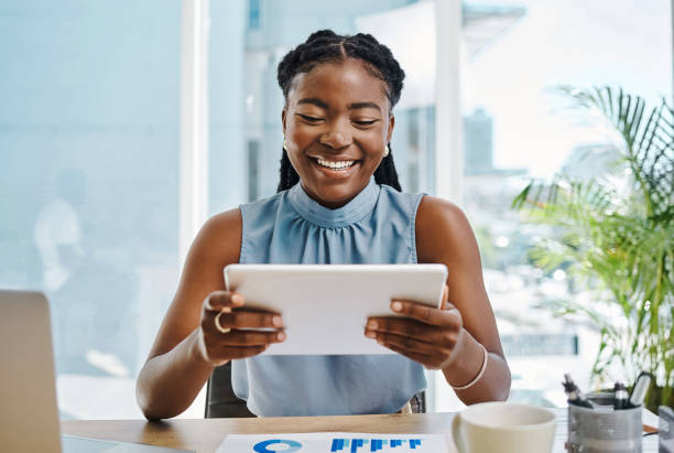 istock Happy young black businesswoman using a digital tablet while analysing graphs in an office alone 1394347634