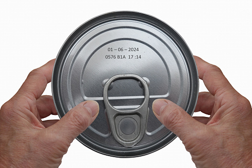 Hands holding a tin can with an expiration date marked on it