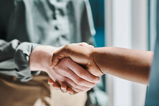 istock Two businesspeople shaking hands while meeting in an office 1394348603