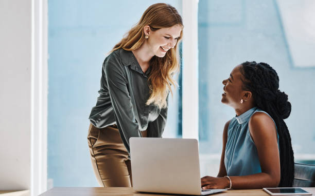 Two confident young businesswomen having a discussion while working together on a laptop in an office stock photo