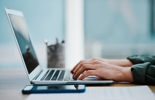 Hands of a caucasian businesswoman using a laptop in an office alone