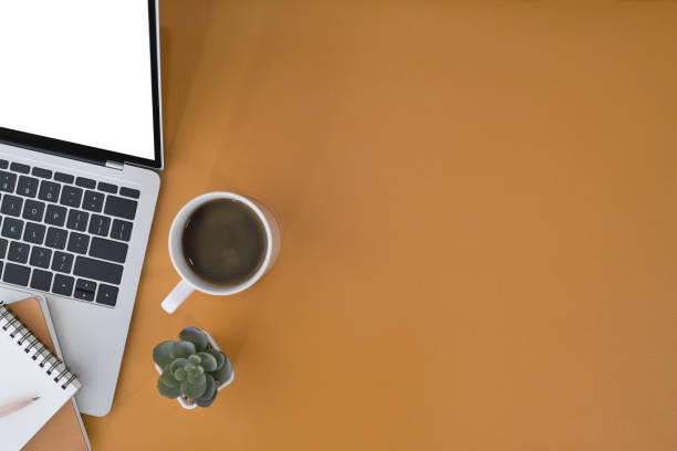 istock Laptop computer, coffee cup and  notebook on yellow background. Stylish workplace, Flat lay. 1394354498