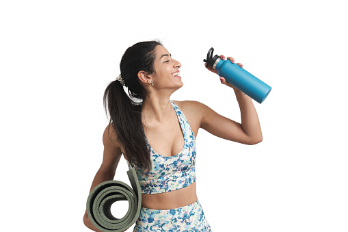 Young Venezuelan sportswoman drinking water and laughing with a mat. Isolated over white background.