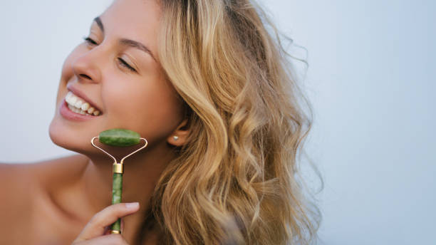 istock Beautiful young woman making face massage using jade roller outdoors. Natural skin care. 1394356744