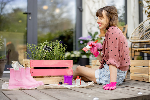 Mujer pintando caja de madera, haciendo algunas tareas domésticas de renovación al aire libre photo