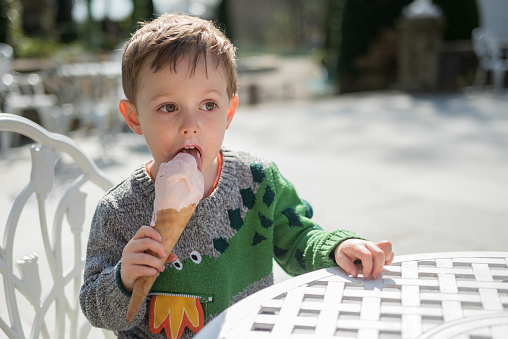 Young boy (2 years 10 months) eating strawberry ice cream on a sunny spring day.