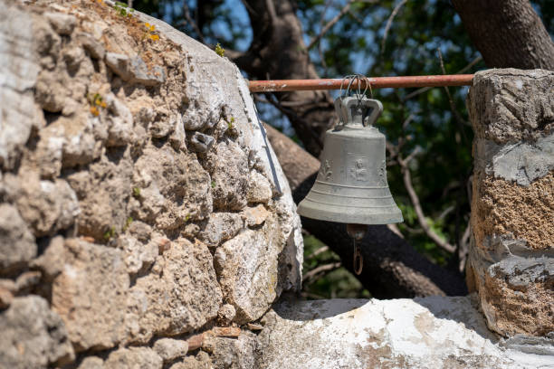 Old metal bell in a farm on a stone wall.