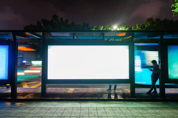 giovane in attesa dei mezzi pubblici alla fermata dell'autobus dell'ora di punta a shenzhen, in cina - billboard foto e immagini stock