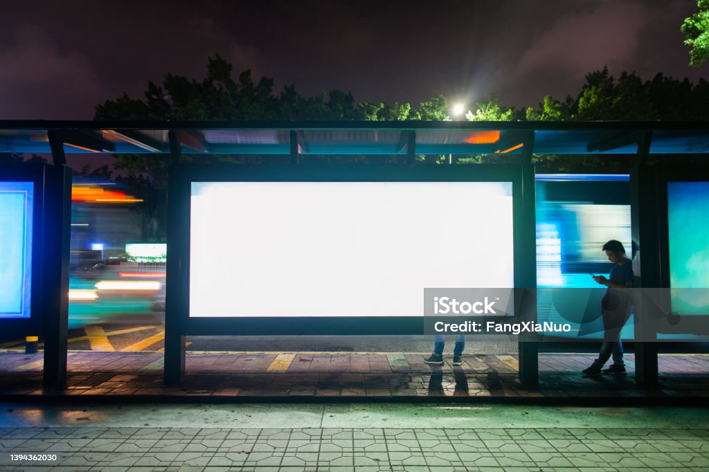 Young man waiting for public transportation at rush hour bus stop in Shenzhen, China Billboard Stock Photo