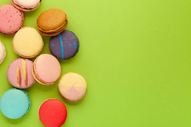 istock Macarons or macaroons with different flavors on green background. Flat lay, copy space 1394363065