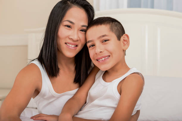 istock Happy asian mom hugging son in bed 1394363722