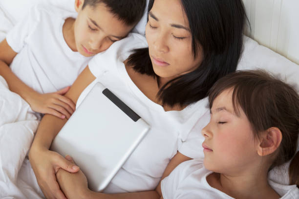 Asian mom and children asleep after reading stock photo