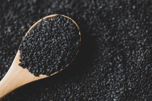 Black sesame seeds in wooden spoon pile and spread