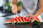 Nice adult woman with watermelon in the kitchen