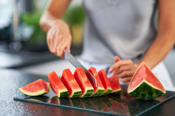 Nice adult woman with watermelon in the kitchen stock photo